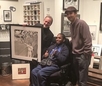 Jay Goldberg presenting artwork to a young man in a wheelchair.
