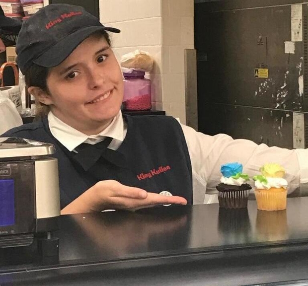 Meghan at the King Kullen bakery counter showing off her beautifully iced cupcakes.