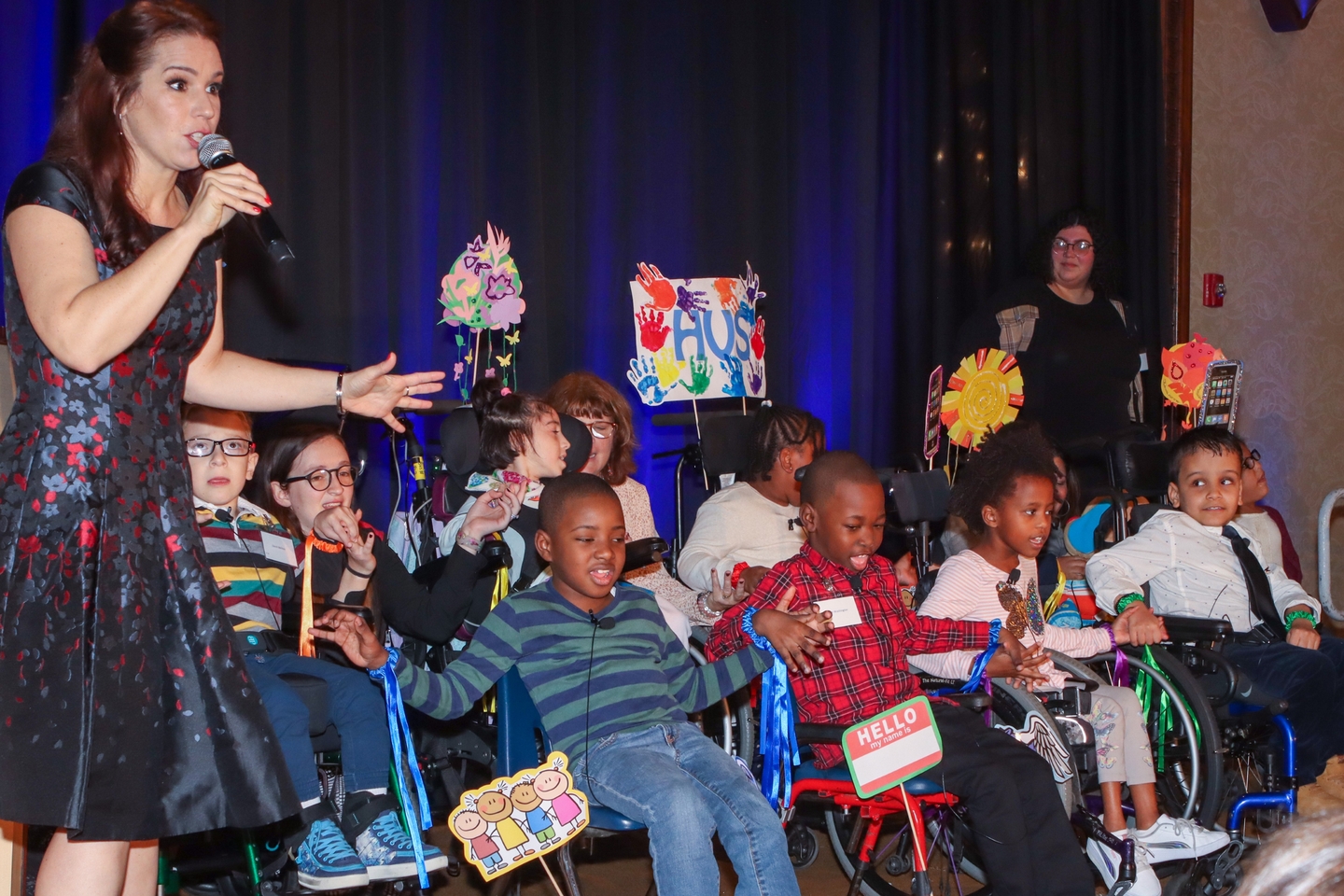 Broadway star Chilina Kennedy singing on stage with students at the Reach for a Star Luncheon