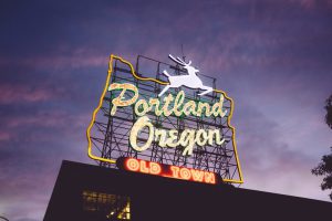 Neon sign that reads Portland Oregon Old Town, on top of a building.